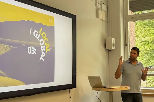 A large screen on the wall and a man. Photo